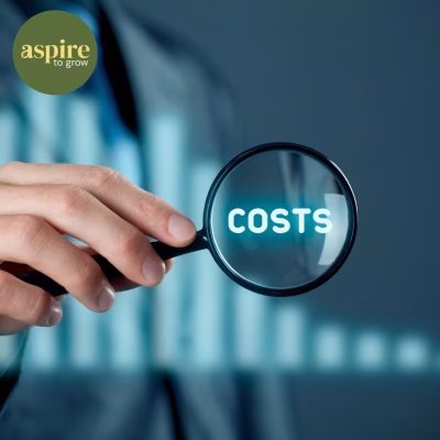 Person holding a magnifying glass focusing on the word "COSTS" with the Aspire to Grow logo in the corner.